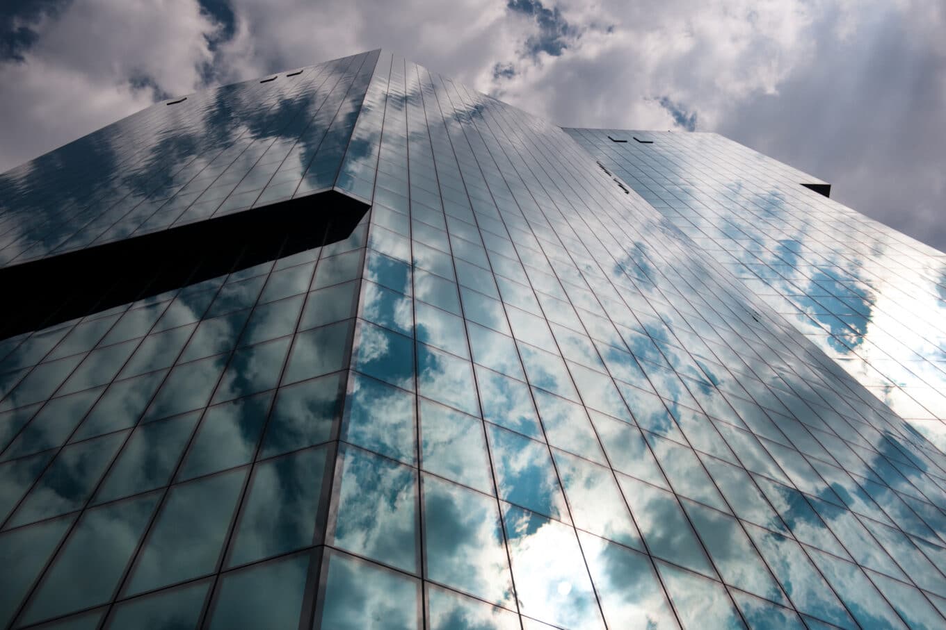 Die Glasfassade des Prime Towers Zürich reflektiert den bewölkten Himmel und erweckt den Eindruck, als würde das Gebäude nahtlos in den Himmel übergehen.