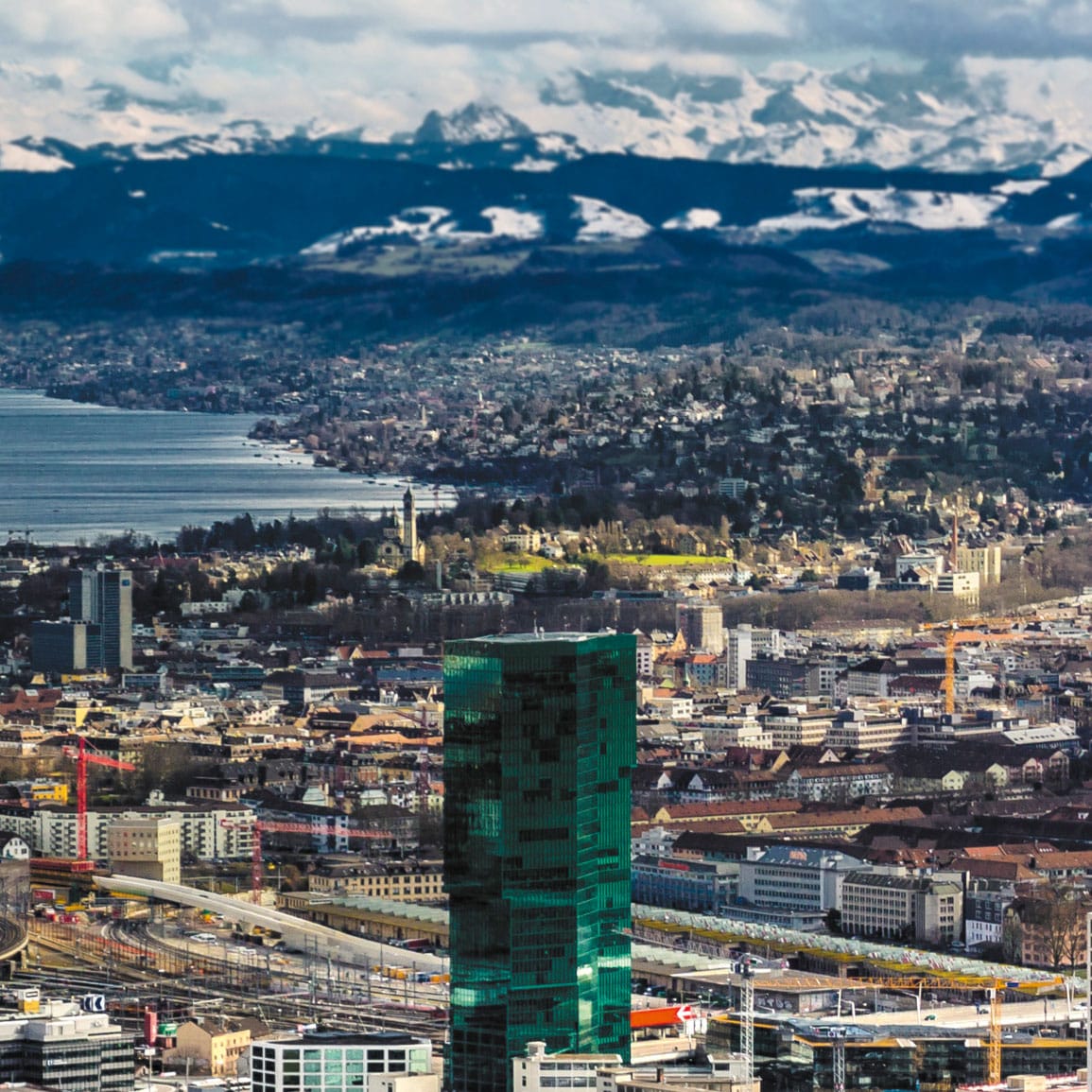 Luftaufnahme auf Zürich mit seinem See, mit schneebedeckten Bergen im Hintergrund.