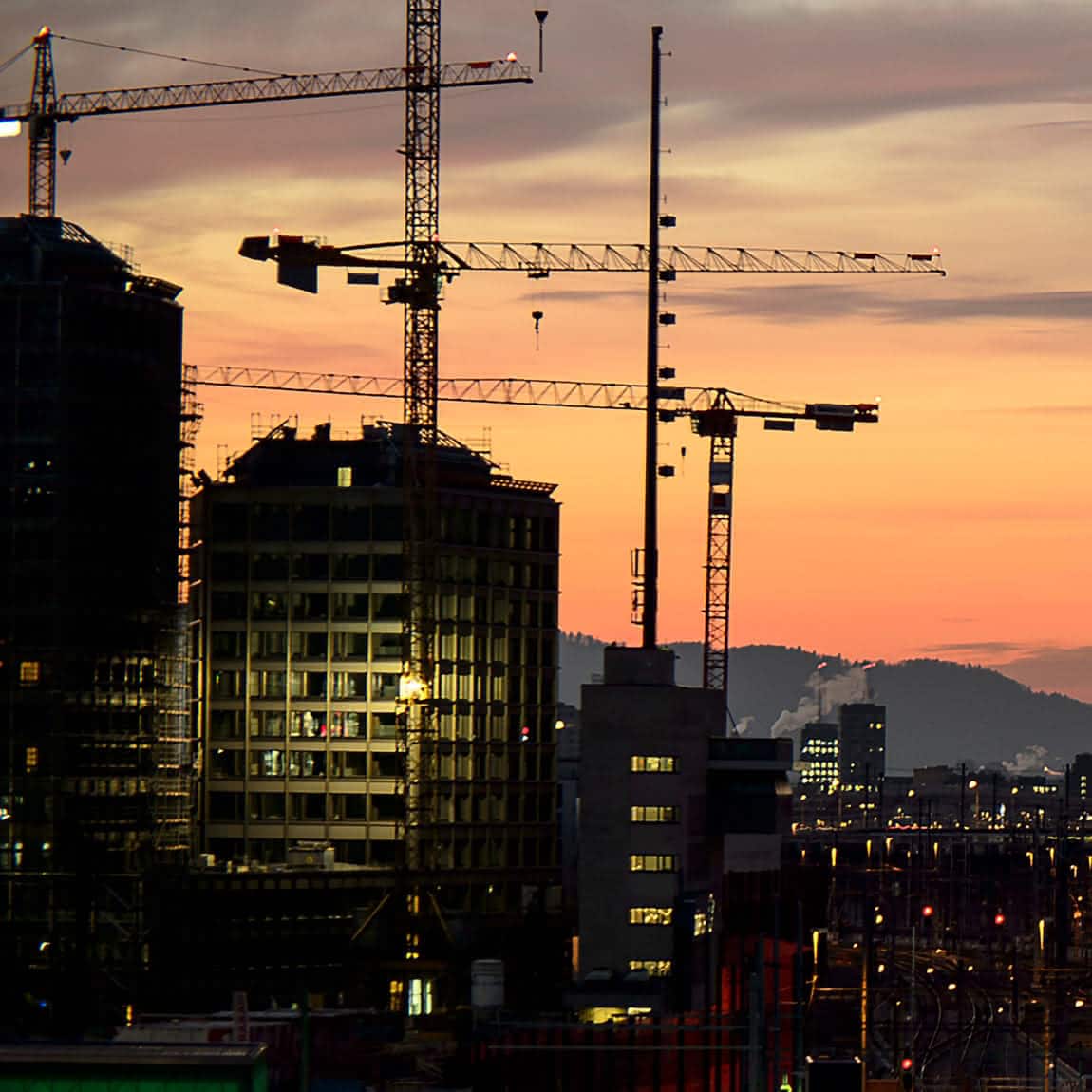 Die Skyline von Zürich bei Sonnenuntergang mit Hügeln im Hintergrund.